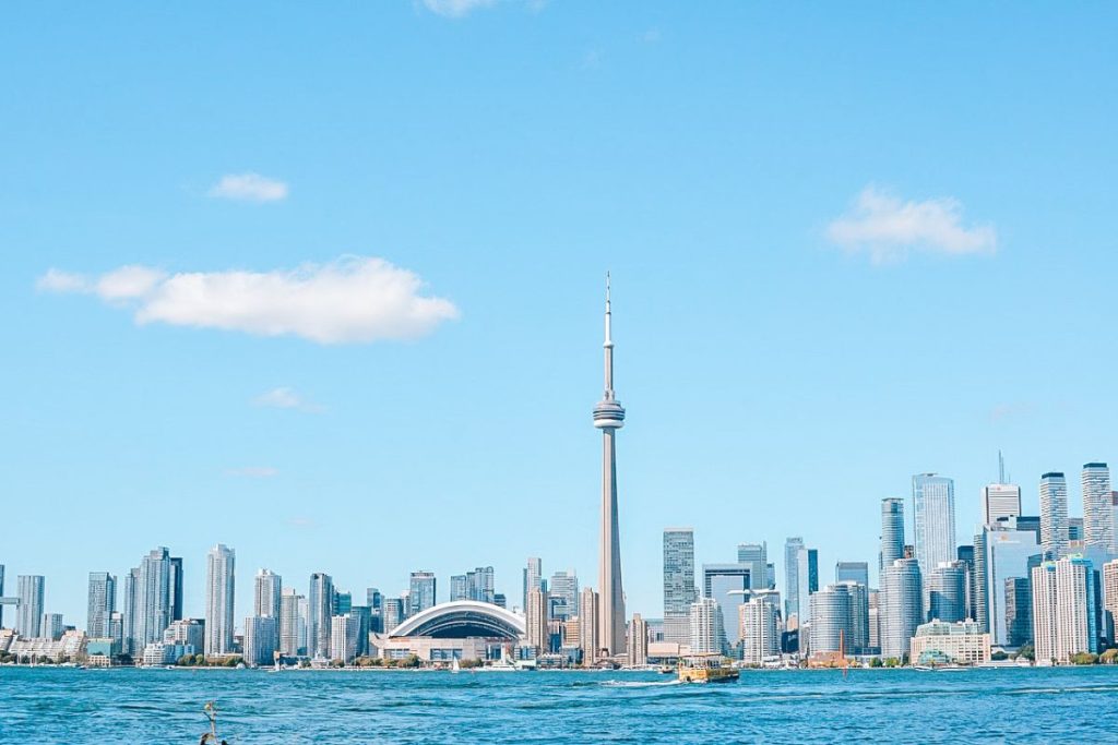 Discover the best things to do in Toronto: Toronto skyline with the CN Tower and Rogers Centre viewed from across the water on a clear, sunny day.