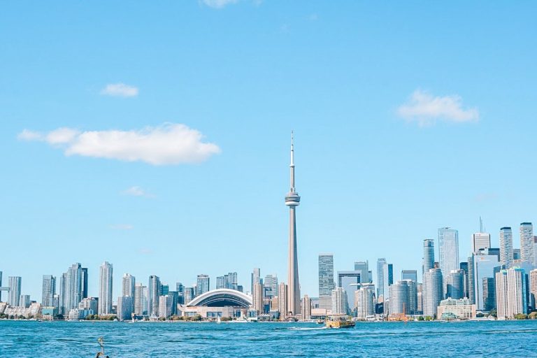 Discover the best things to do in Toronto: Toronto skyline with the CN Tower and Rogers Centre viewed from across the water on a clear, sunny day.