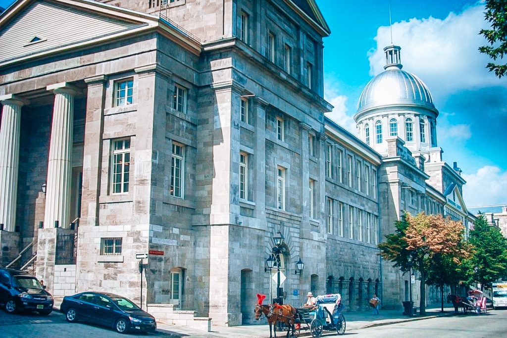 How to spend 24 hours in Montreal: Historic stone building with a silver dome and horse-drawn carriages in Old Montreal, Canada.