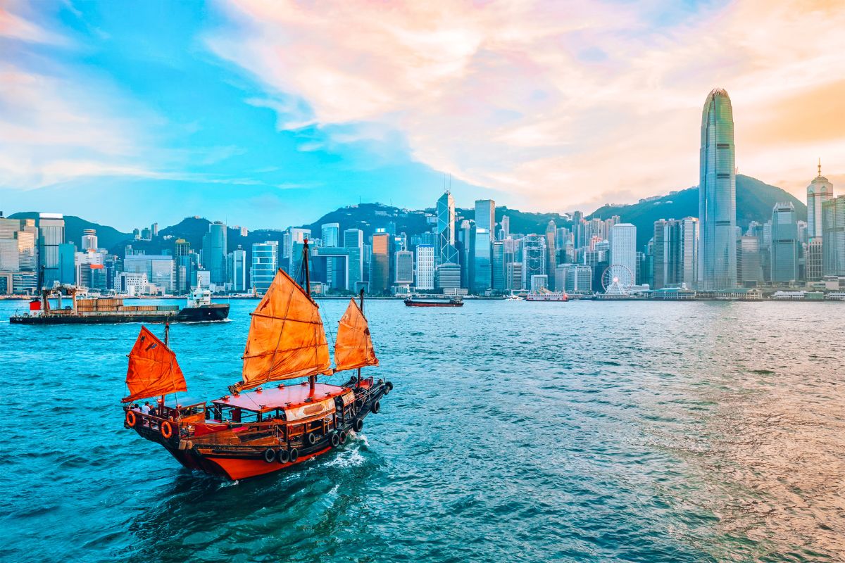 How to spend 48 hours in Hong Kong: A traditional red-sailed junk boat sailing across Victoria Harbour with the modern skyline of Hong Kong in the background.