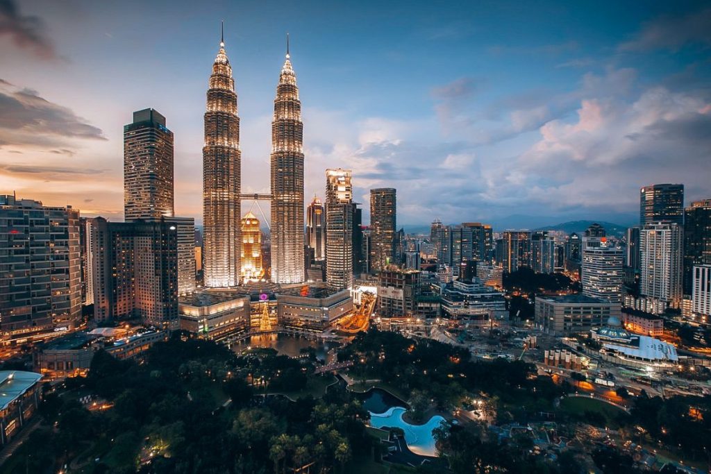 The Ultimate Kuala Lumpur Guide on a Budget: Night view of Kuala Lumpur city skyline with the illuminated Petronas Twin Towers and surrounding skyscrapers.