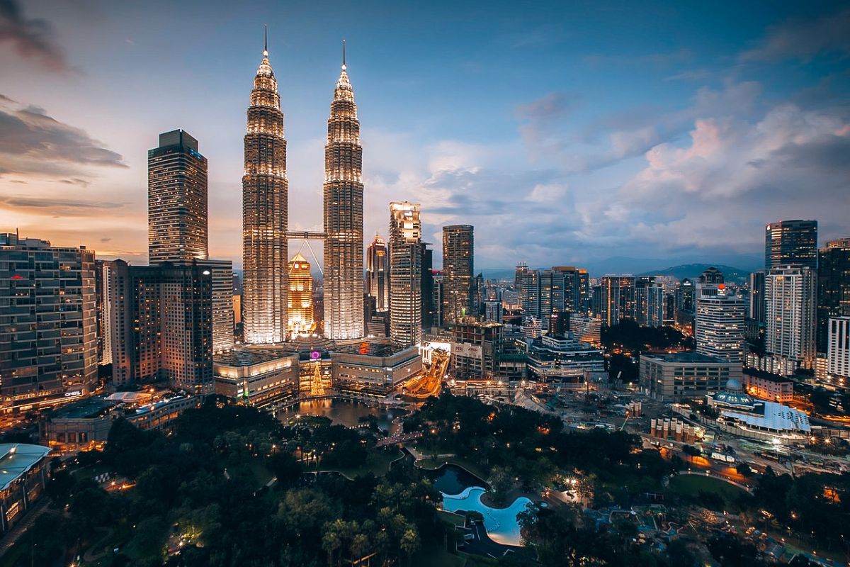 The Ultimate Kuala Lumpur Guide on a Budget: Night view of Kuala Lumpur city skyline with the illuminated Petronas Twin Towers and surrounding skyscrapers.