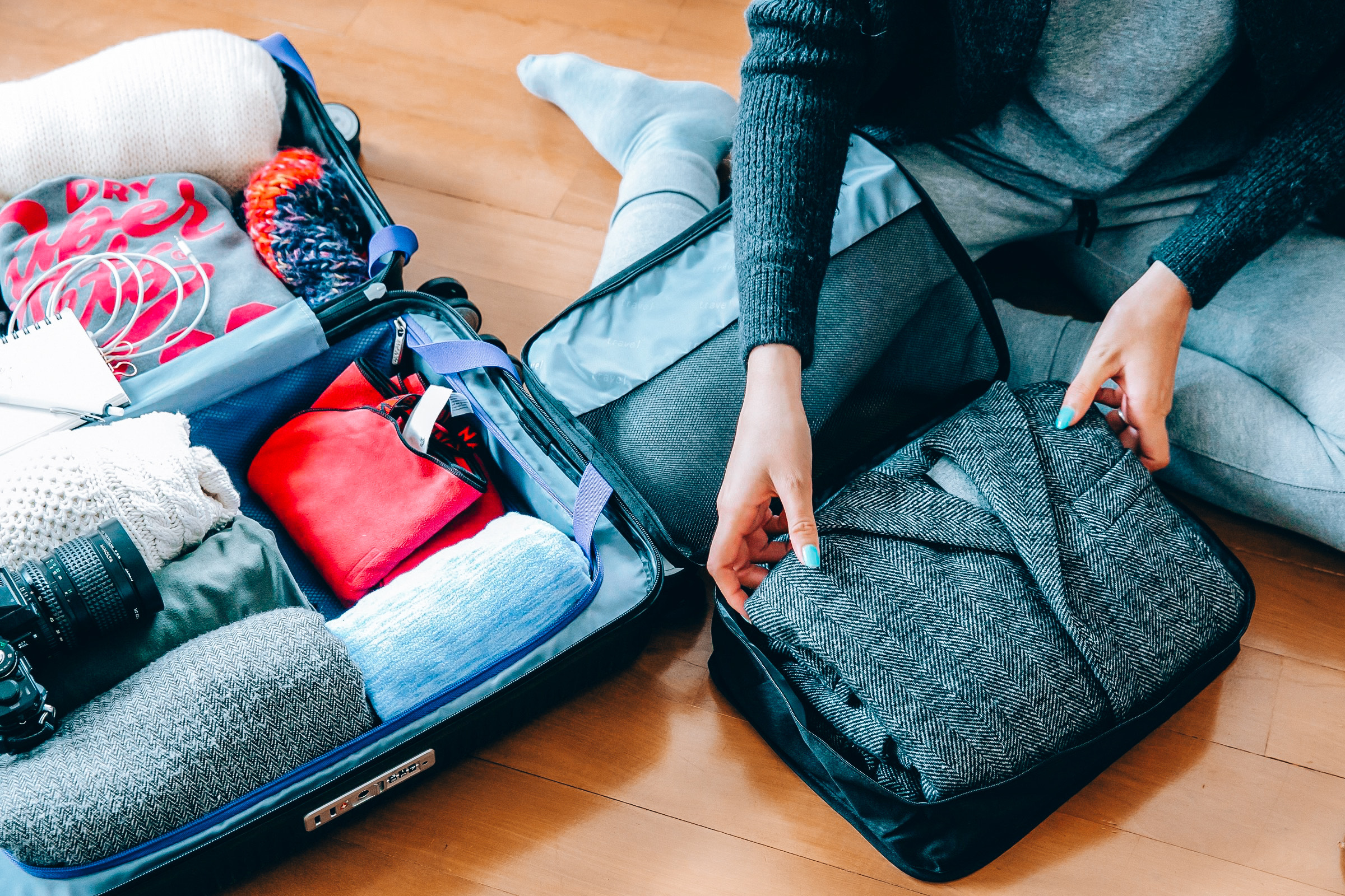 Traveller packing clothes into a carry-on suitcase using packing cubes, an organised and practical example of how to prepare with the best carry-on backpack for travel.