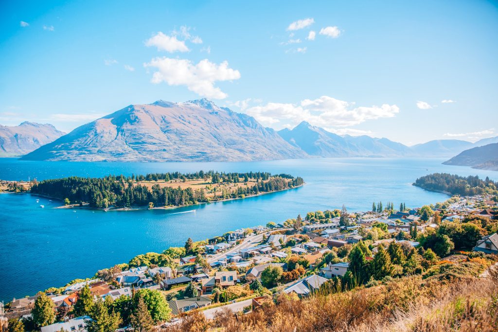 The Best Places to Travel Solo in 2025: Panoramic view of Queenstown, New Zealand, with clear blue skies, Lake Wakatipu, and surrounding mountains.