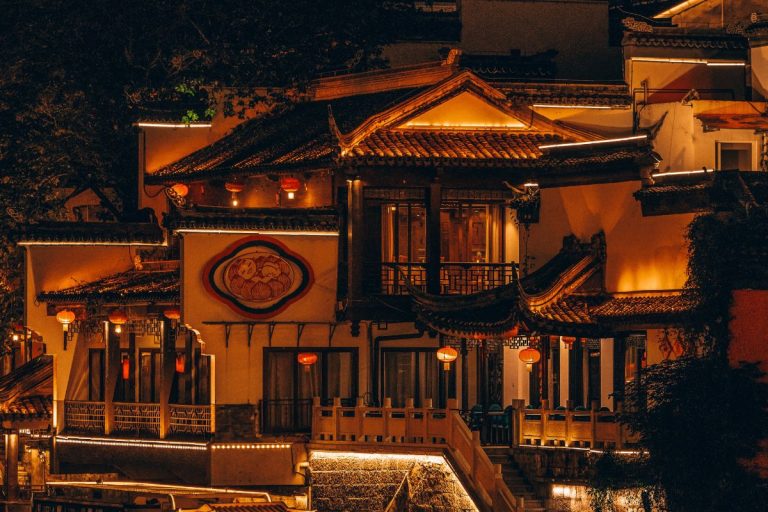 Traditional Chinese-style hotel in Nanjing illuminated at night with red lanterns, ornate tiled roofs, and warm golden lighting, showcasing the cultural charm of the Best Hotels in Nanjing.