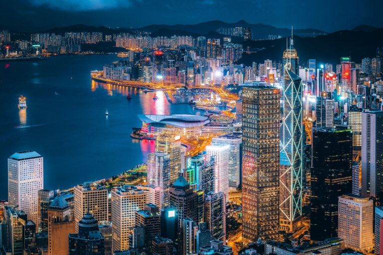 A vibrant night view of Hong Kong’s skyline with skyscrapers lit up along Victoria Harbour, including the Bank of China Tower and the Hong Kong Convention and Exhibition Centre, perfect for a Hong Kong Travel Guide.