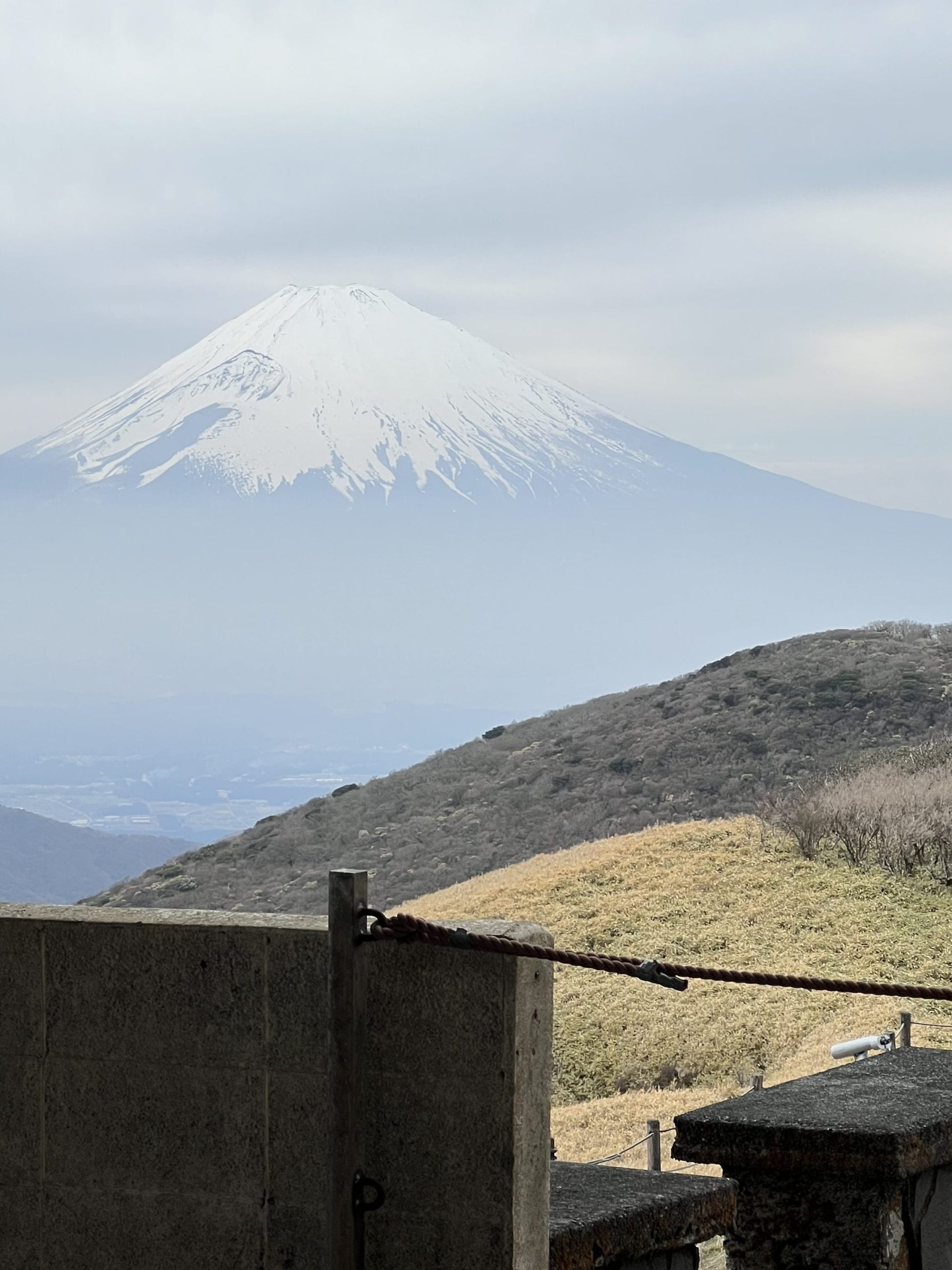 A snow-capped volcanic mountain can be seen behind green hills.